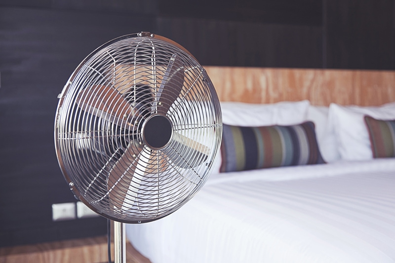 Improve Your Home’s Indoor Air Quality, Old electric fan near the bed in the room