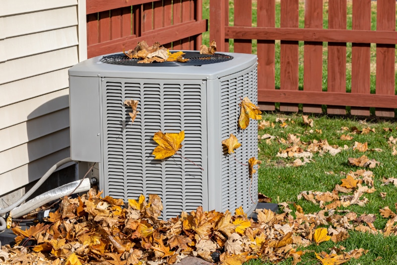 Fall HVAC Maintenance. Air conditioner in fall leaves.