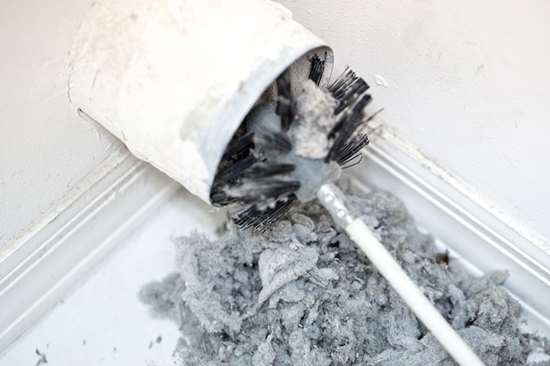 Dry Vent Cleaning. Lint being removed with a brush from a dryer vent.